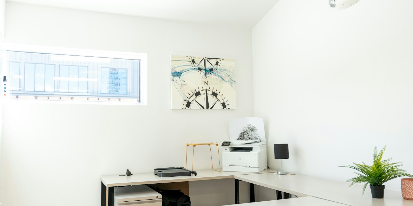 A bright, empty modern office with a desk beside a window